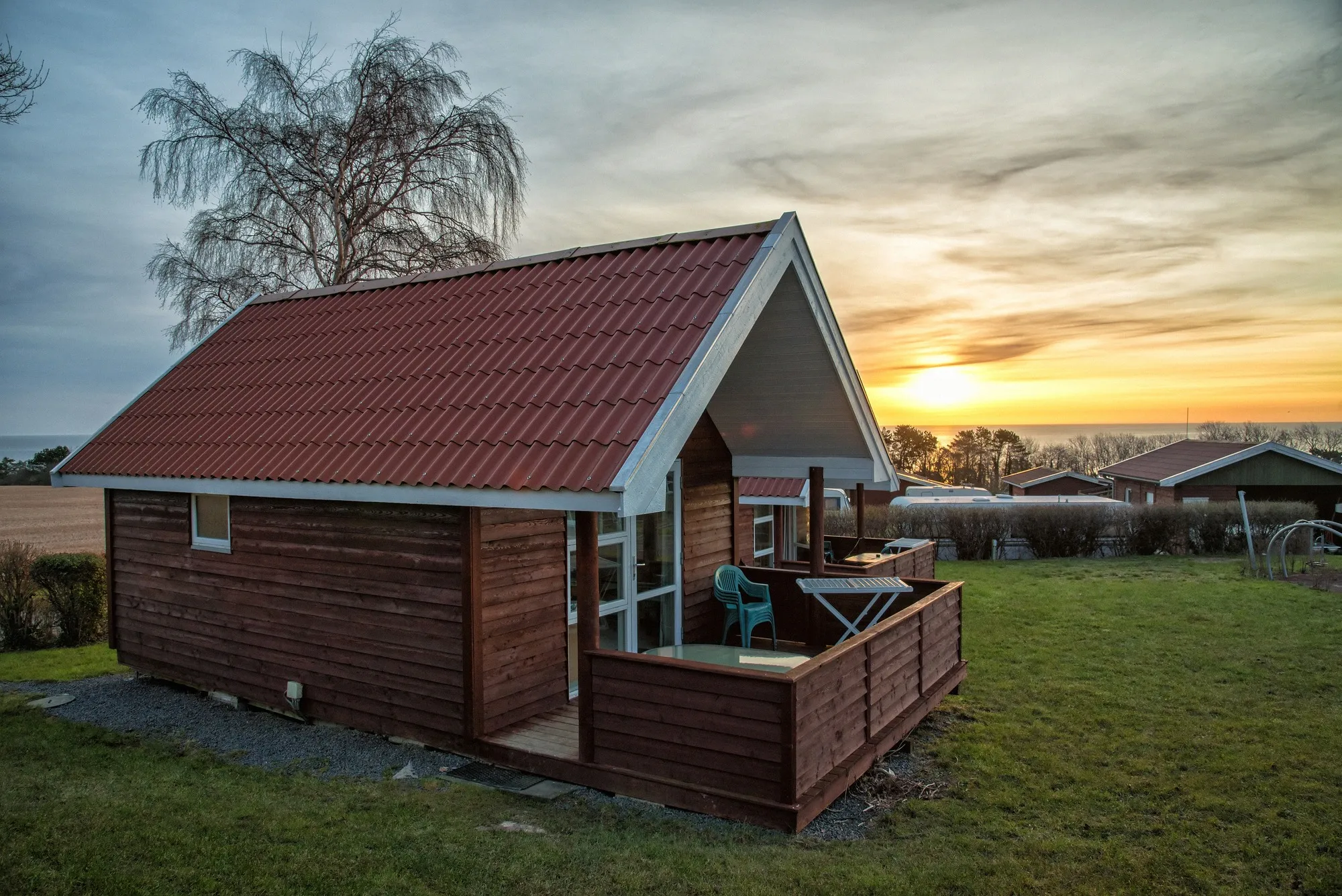 Kleines Holz-Ferienhaus mit rotem Dach im Abendlicht mit Blick auf die Ostsee