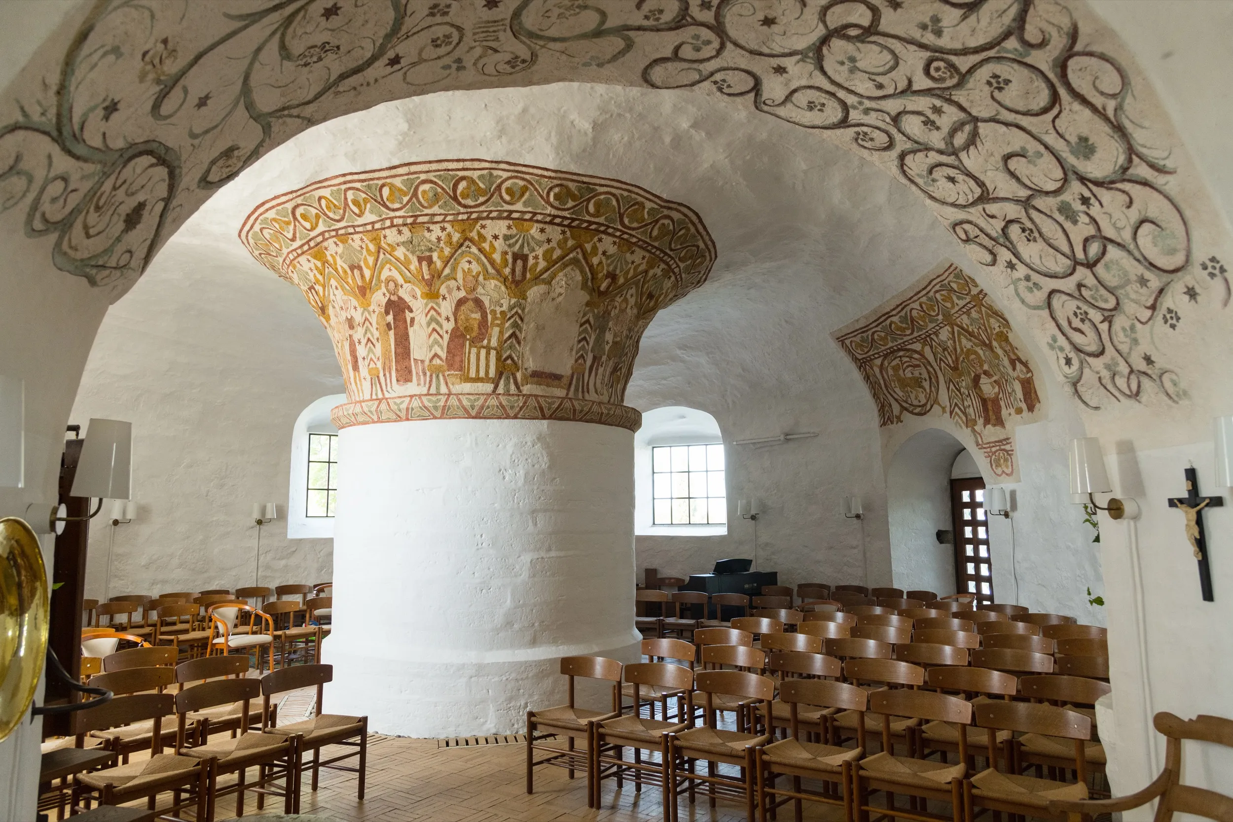 Innenraum der Nyker Kirke mit weißem Zentralpfeiler und romanischen Fresken