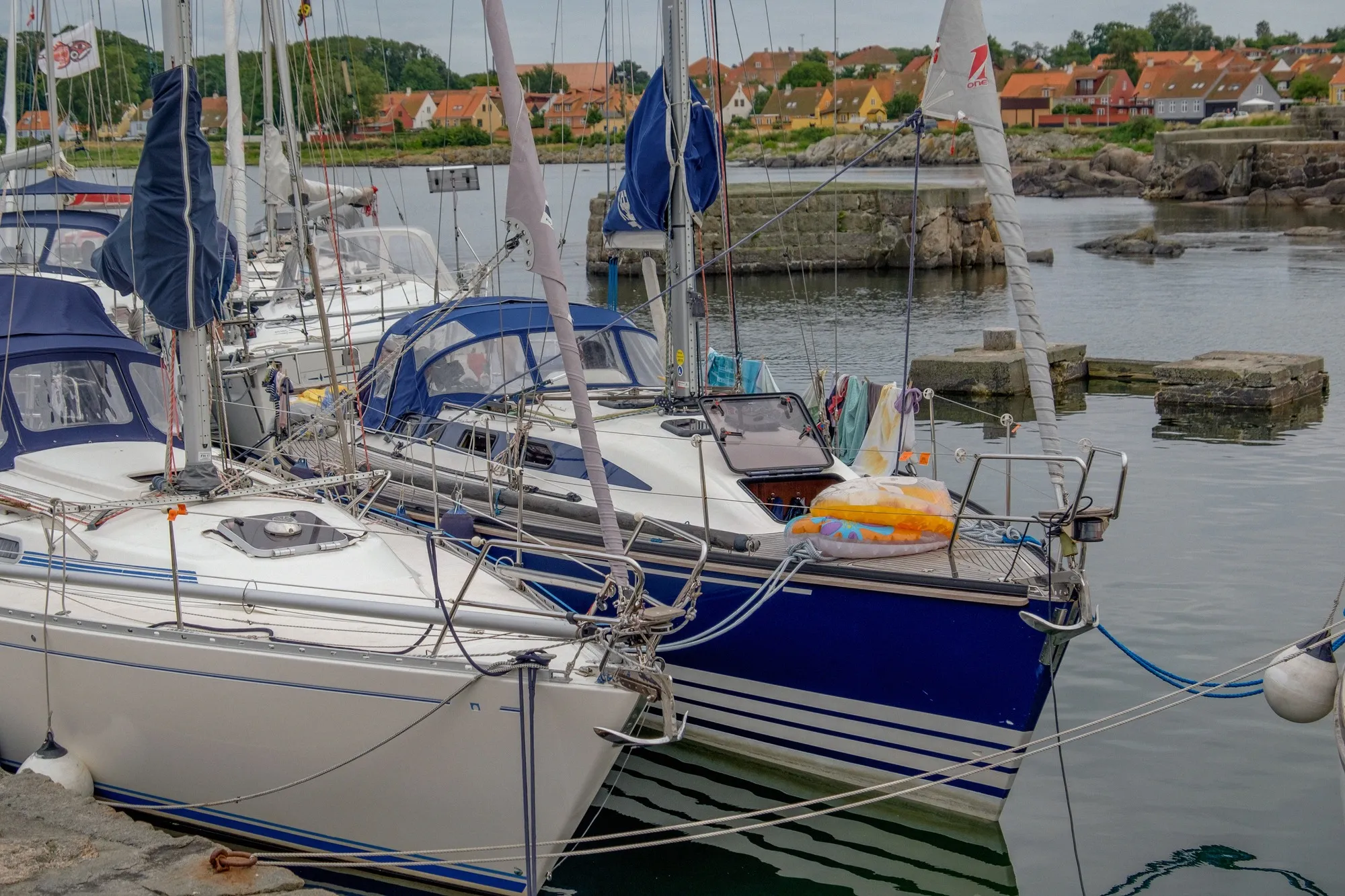 Segelboote am Kai des Hafens von Svaneke, dahinter rote Dächer des Ortes