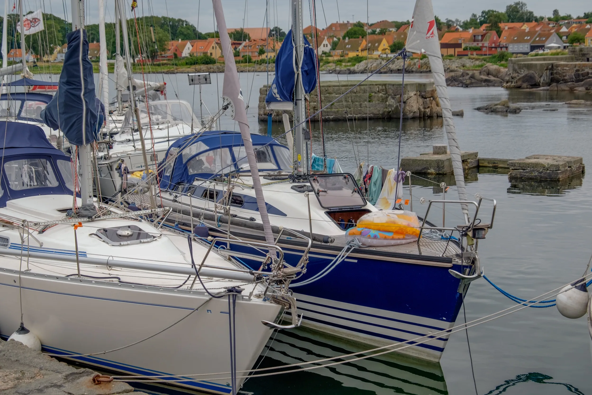 Segelboote am Kai des Hafens von Svaneke, dahinter rote Dächer des Ortes