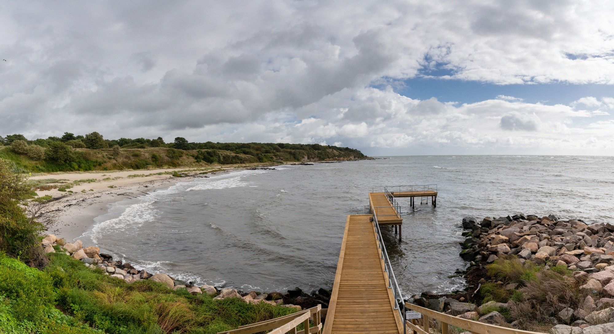 Naturbelassener Strand mit Sand und Gras in Rønne mit Blick auf die Stadt.