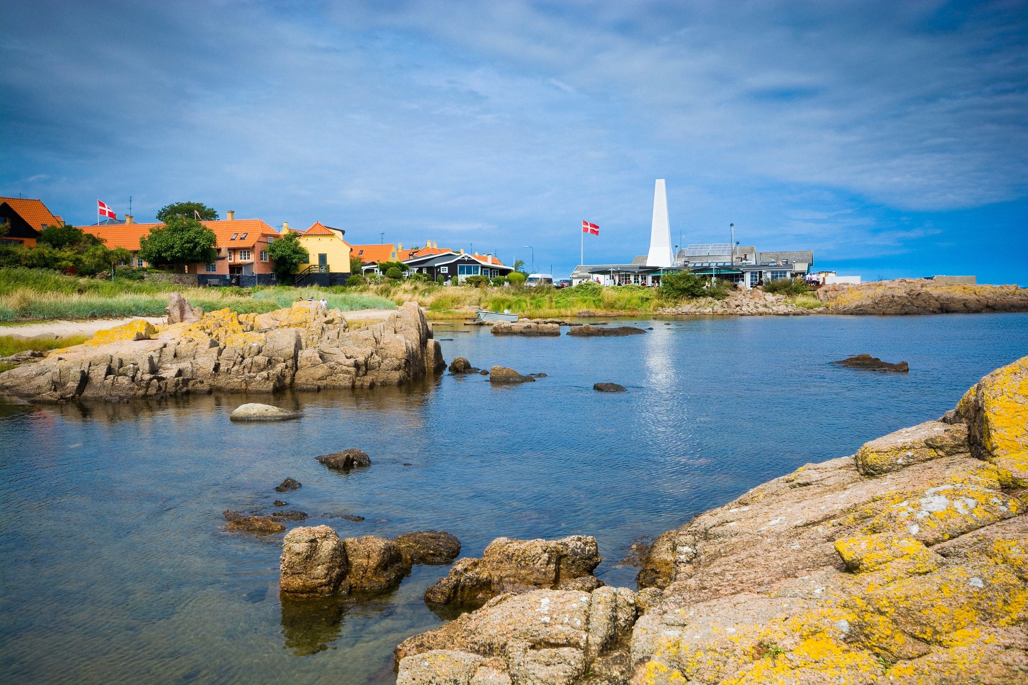 Rocky cove on the north coast near Allinge. Quiet rocky cove with clear water and Danish flags on the north coast near Allinge