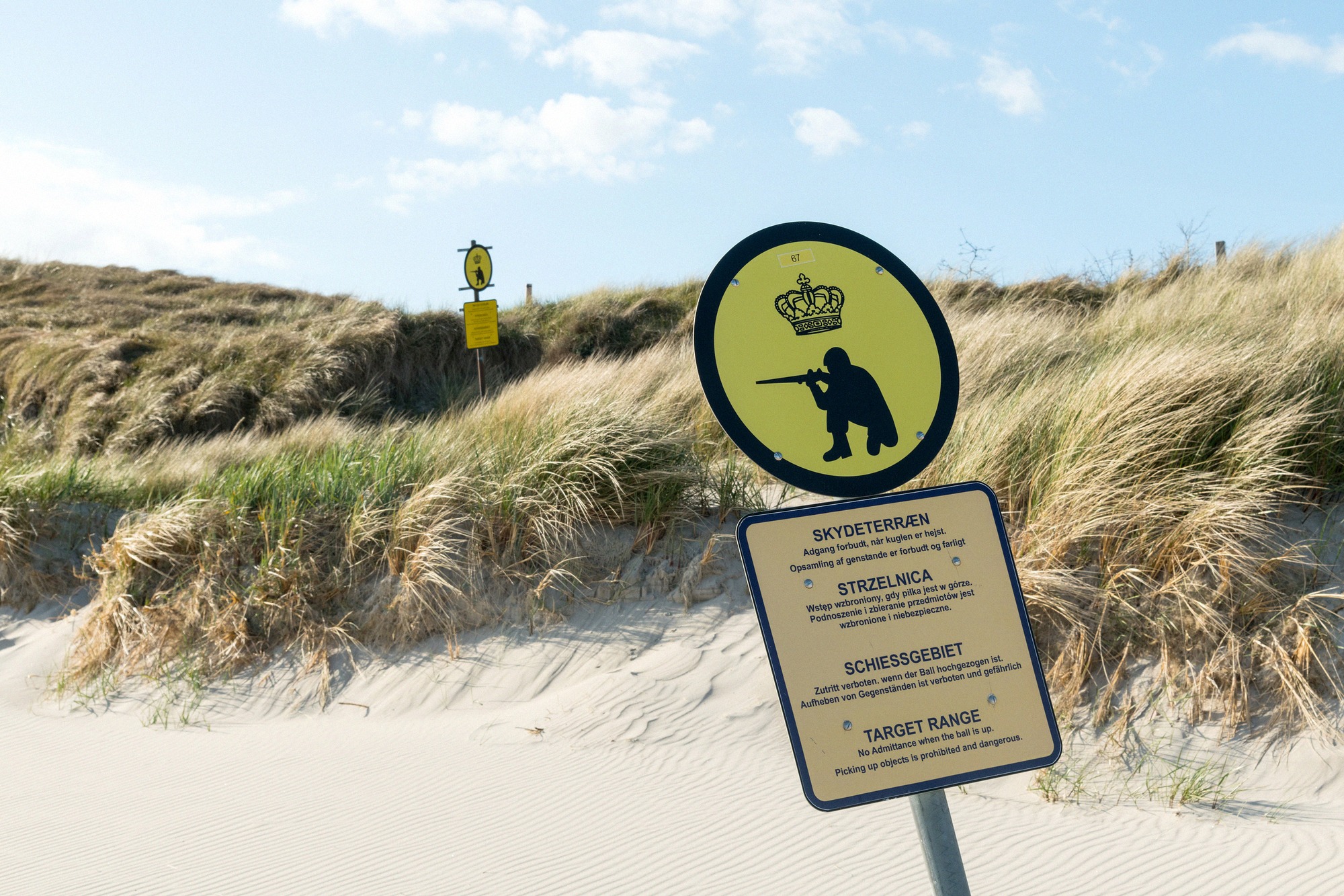 Warning signs at the Raghammer firing range: the area is closed during exercises. Multilingual military warning signs in the sand dunes