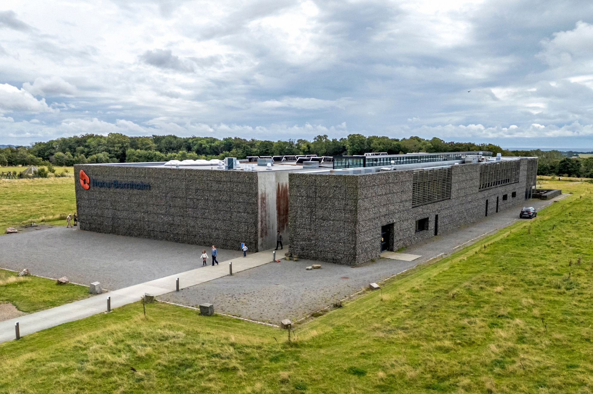 Aerial view of the NaturBornholm museum with its gabion facade amid green fields