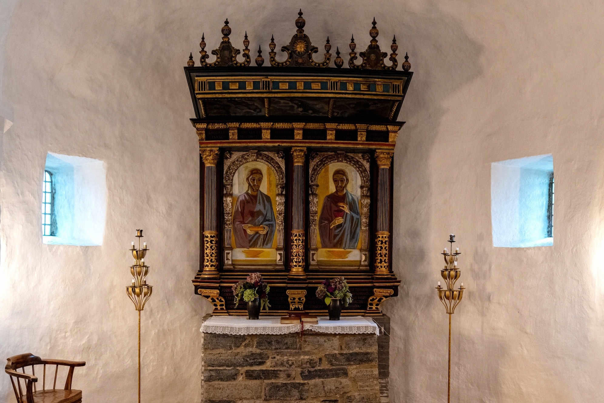 The altar with its Renaissance retable in the apse. Altar of Østerlars Church with its Renaissance retable in the whitewashed apse