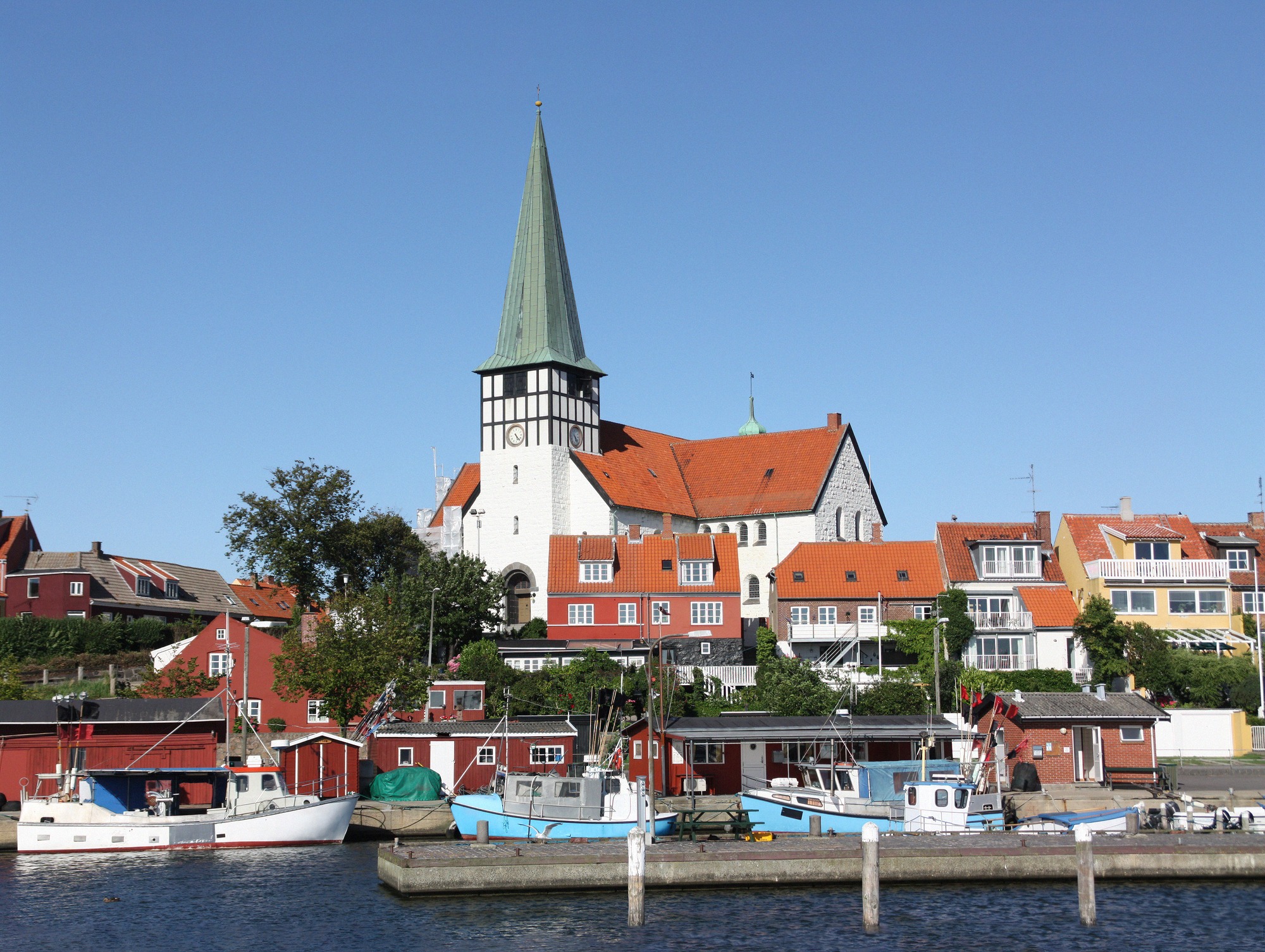 Sankt Nicolai Kirke rising above the harbour houses. View from the harbour towards Sankt Nicolai Kirke and colourful harbour houses in Rønne