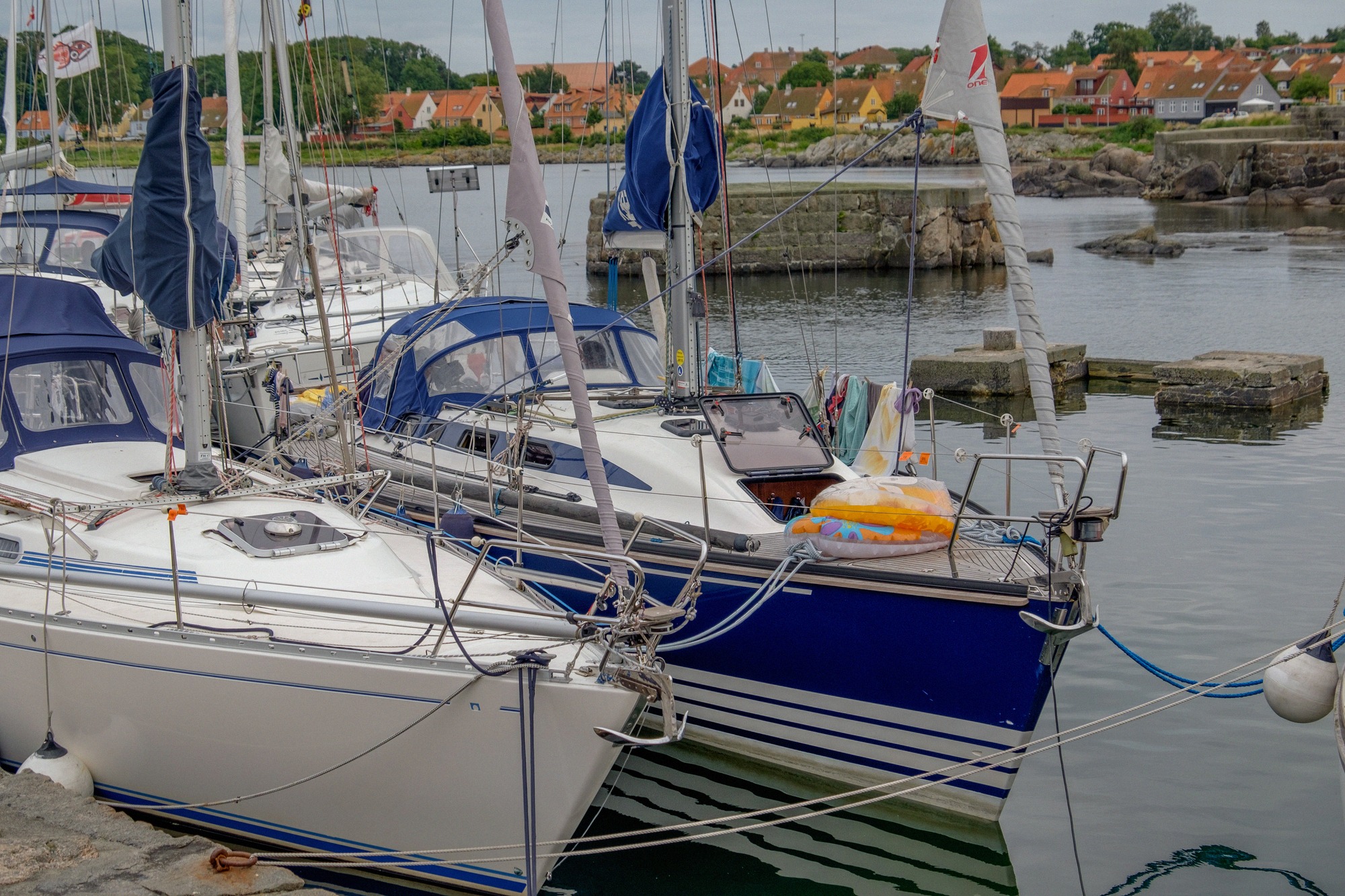Sailing boats in Svaneke's rock harbour. Sailing boats moored at the quay in Svaneke harbour, with the town's red roofs behind
