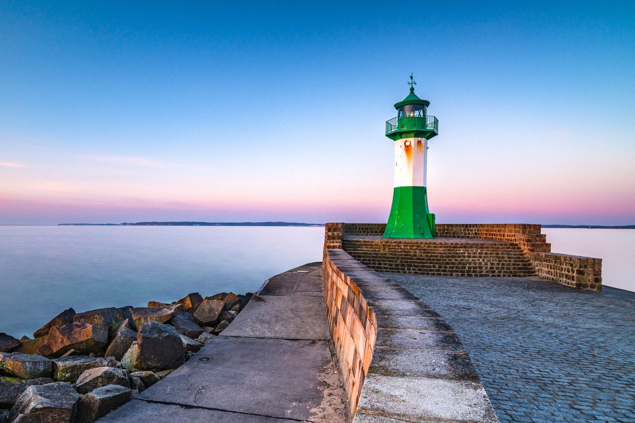 De groen-witte vuurtoren bij de haveningang van Sassnitz op Rügen tijdens de avondschemering.